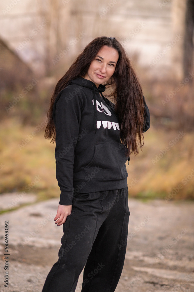 Portrait of a young beautiful cheerful dark-haired girl in a dark tracksuit. Portrait of a young beautiful cheerful dark-haired girl in a dark tracksuit.