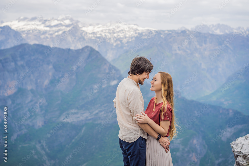 Man and woman happy couple tourists on background of Breathtaking panoramic view of the Grlo Sokolovo gorge in Montenegro. In the foreground is a mountain, the flat side of which forms a cliff, and