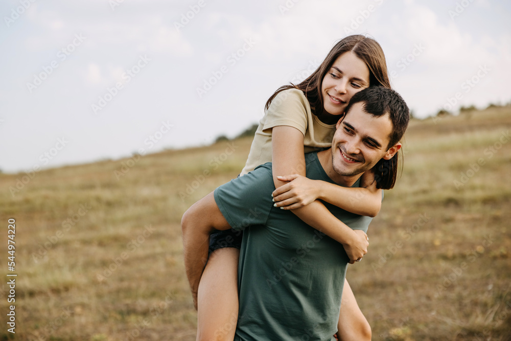 Happy couple of young man and woman in a field, outdoors, hugging