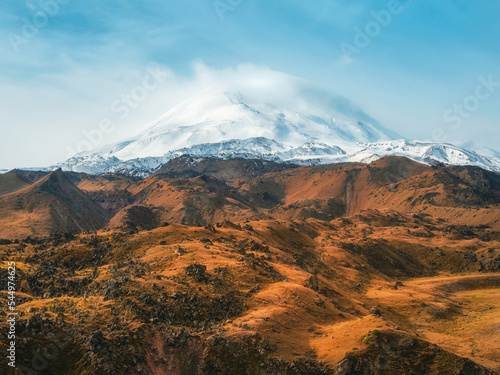 Bright white snowy peak of Mount Elbrus above the autumn rocky plateau. Autumn Elbrus. Autumn in the Caucasus mountains. White snow big mountains. Snow peaks.