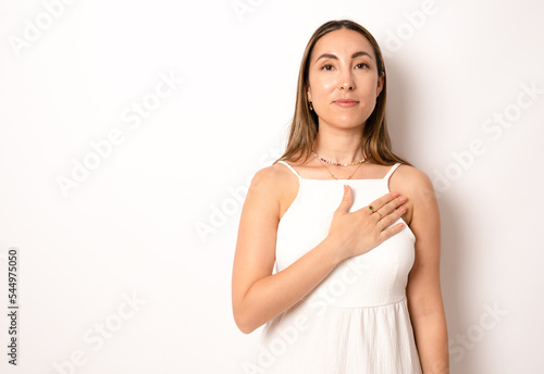 Young woman in casual dress Swearing with hand on chest, making a loyalty promise oath photo