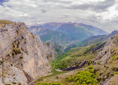 Breathtaking panoramic view of the Grlo Sokolovo gorge in Montenegro. In the foreground is a mountain, the flat side of which forms a cliff, and the ridge is overgrown with trees