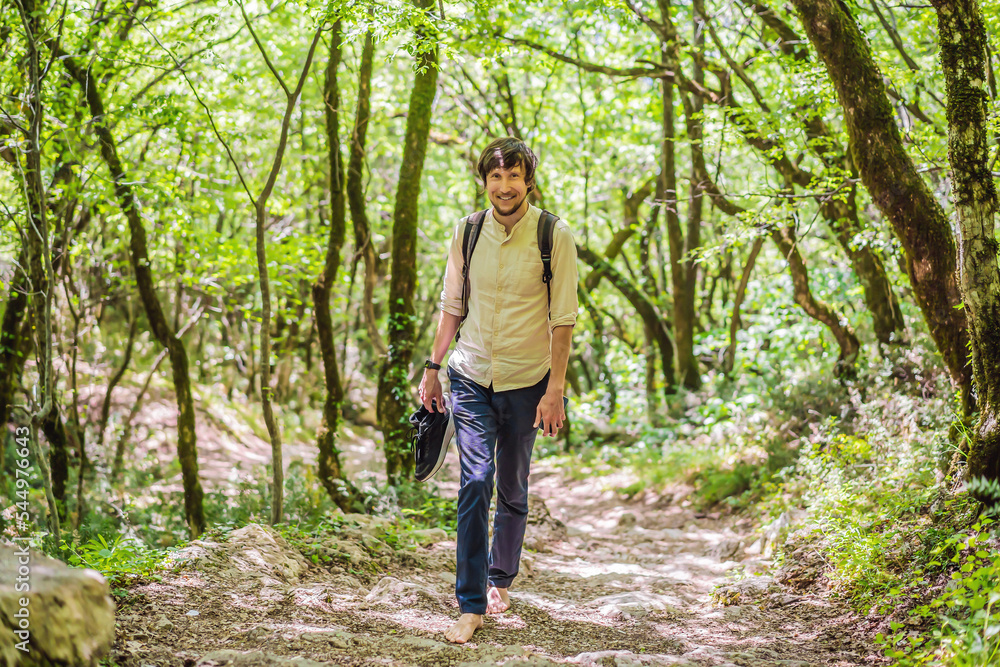 Man tourist climb barefoot the mountain to the Ostrog. It is a tradition to climb barefoot. Monastery of Ostrog, Serbian Orthodox Church situated against a vertical background, high up in the large