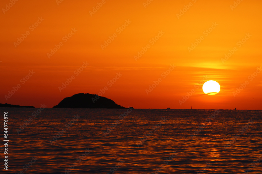The Sun Rising over a small island off the coast of Santa Eulalia, Ibiza, Spain.