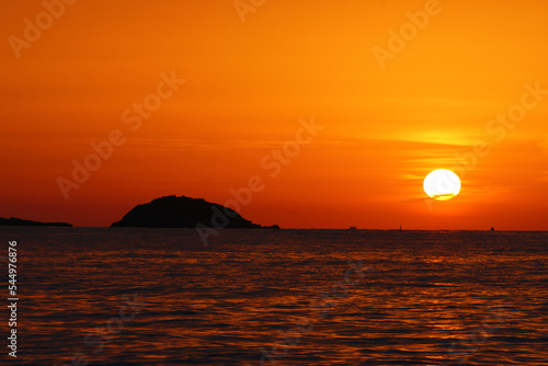 The Sun Rising over a small island off the coast of Santa Eulalia  Ibiza  Spain.