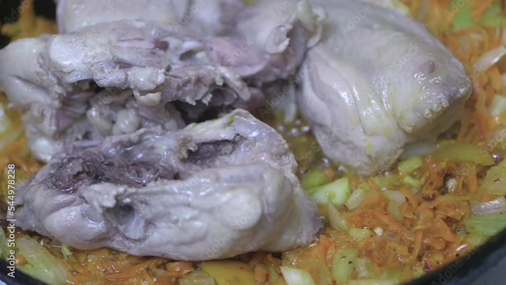 adding chicken backs of cheap meat, to vegetables fried in a pan in sunflower oil, close-up adding chicken backs of cheap meat, to vegetables fried in a pan in sunflower oil, close-up