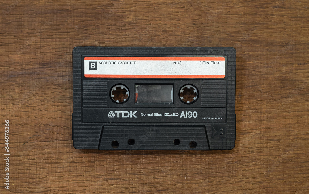TDK audio cassette in black on a wooden table.A tape recorder for listening  to music.