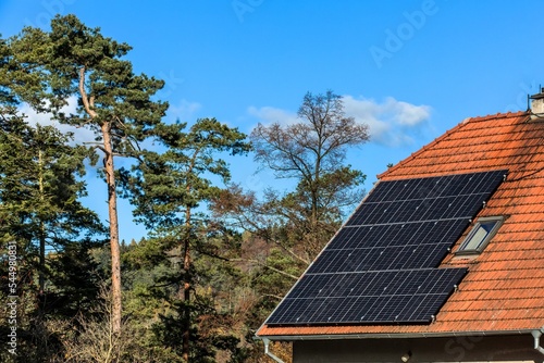 Old house in the Czech Republic with a solar panel roof in nature. Photovoltaic panels on the roof. Saving electricity. Ecological concept.