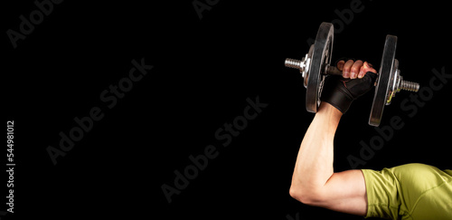 Men arm hand lifting dumbbell close up. Ad banner, black background with space for text