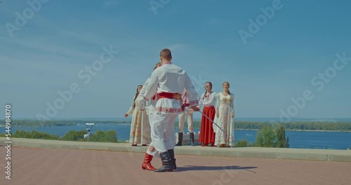 Woman and a man in national costumes with beautiful embroidery flank sabers simultaneously, Ukrainian people look at them. Martial historical art of flanking. Fine art of flanking. 4k, ProRes photo