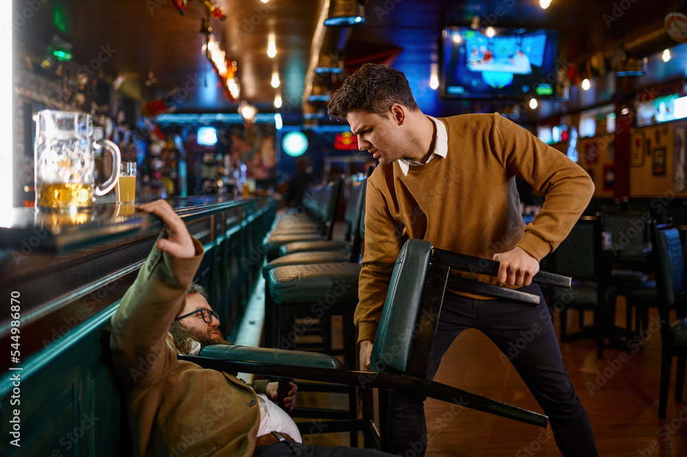 Fight in a pub, angry guy pulling friend with chair