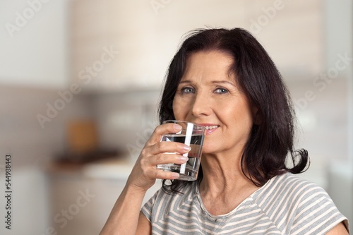 Happy senior woman drinking water at home.