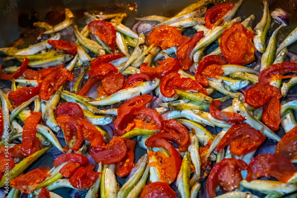 Cooking fish with cherry tomatoes and herbs on parchment in the oven