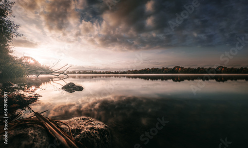 Sonnenaufgang am See mit vielen Reflektionen und einem dramatischen Wolken-Himmel photo