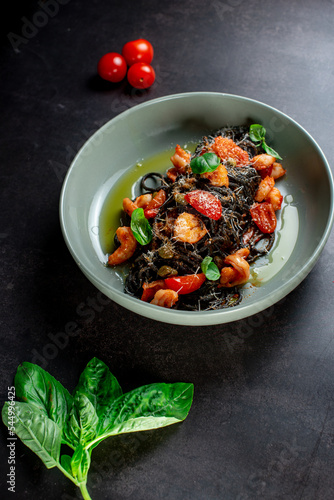 black paste with cuttlefish ink basil ad tomato on blavk background