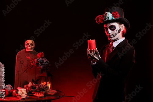 Beautiful model with skull make up holding candle burning in studio  being dressed as santa muerte to celebrate dios de los muertos. Looking like mexican goddess of death on day of the dead.