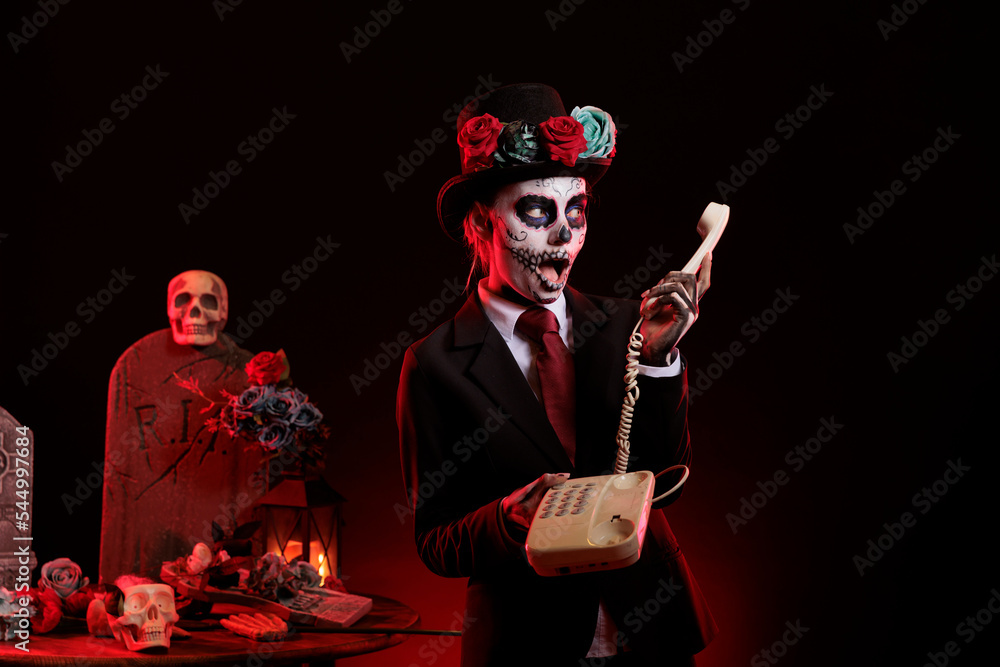 Goddess of death woman using landline phone in studio, celebrating la
