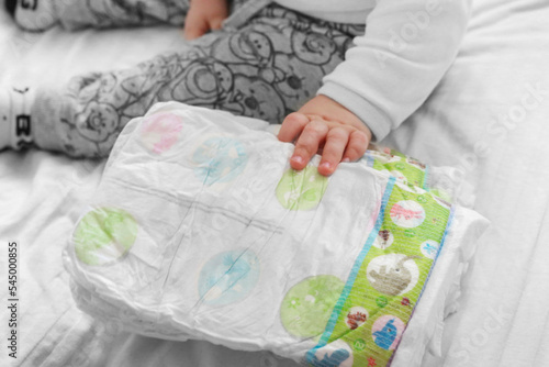 happy baby holding diaper in hands. Close up. baby is surrounded by diapers on a white background