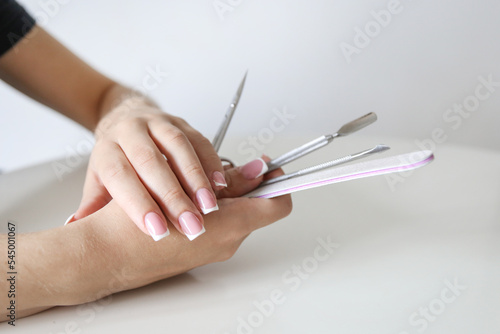 close up of woman hands holding manicure tools on a white background