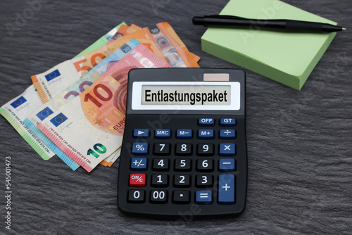 Das Wort Entlastungspaket mit Taschenrechner und Euro Banknoten. photo