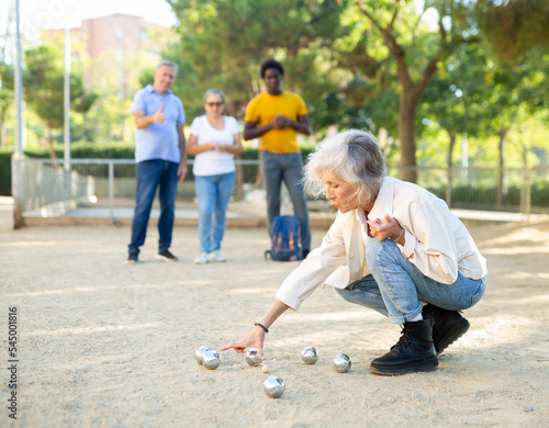 Smiling mature people playing petanque on sand together