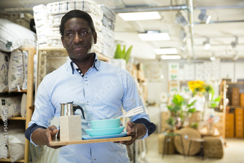 Portrait of smiling african american man with purchases in home furnishings store..