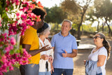 Portrait of multiracial mature adult people standing outside at park on a sunny day and carelessly and friendly communicating to each other