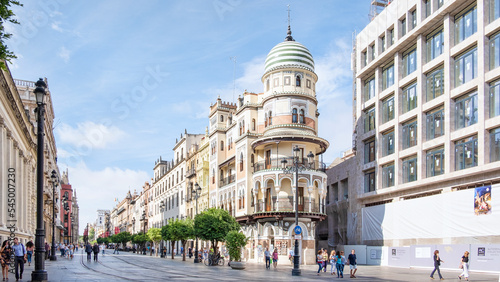 Street view of pedestrians walking along Avda. de la Costitucion, major avenue in the Casco Antiguo district, lined with historical buildings, views of Edificio de la Adriatica, Seville, Spain