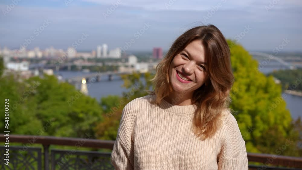 Joyful woman with toothy smile turning looking at camera smiling on sunny day outdoors. portrait of charming positive Caucasian lady posing at background of river and blurred urban city Joyful woman with toothy smile turning looking at camera smiling on sunny day outdoors. portrait of charming positive Caucasian lady posing at background of river and blurred urban city