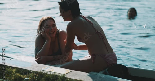 Beautiful female couple flirting and smiling on the lakeshore photo
