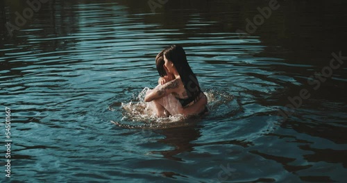 Young couple hugging each other in the lake at sunset photo
