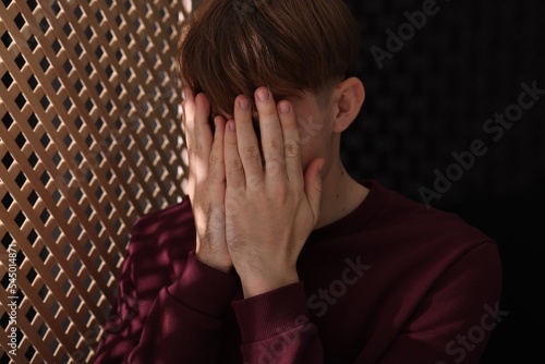 Upset man near wooden partition during confession in booth photo