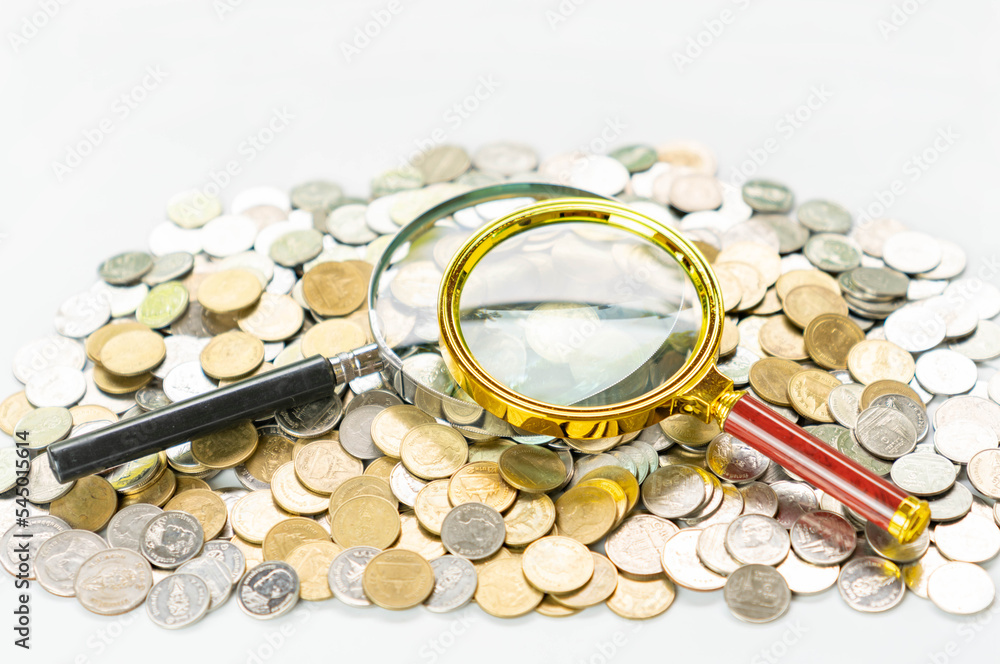Magnifying glass on a pile of money coins. Stock Photo