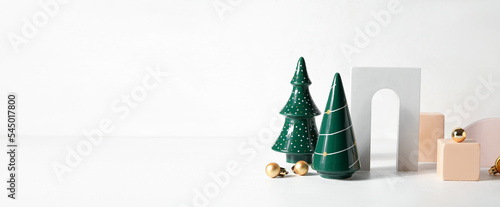 Toy Christmas trees and decor on light background with space for text