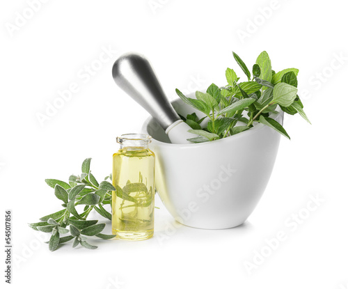 Mortar with different herbs and bottle of essential oil on white background