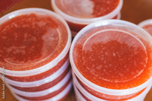 Red caviar plactic jars, rows of salted canned red caviar containers filled to the top on a seafood production, packaging and distribution company, producing conserved salmon red caviar photo