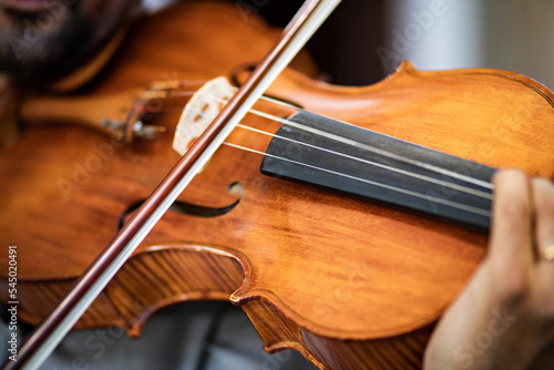 violinista impegnato in concerto di musica classica con vista ravvicinata su corde e archetto photo