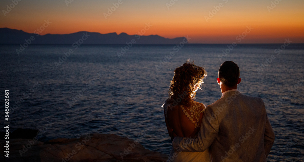 foto che ritrae coppia di sposi in una silhouette da dietro durante un servizio fotografico matrimonialista al tramonto nello scenario di cala rossa a Terrasini in provincia di Palermo