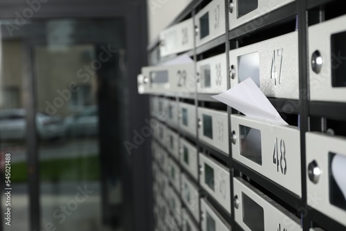 New mailboxes with keyholes, numbers and receipts near entrance in post office, closeup © New Africa