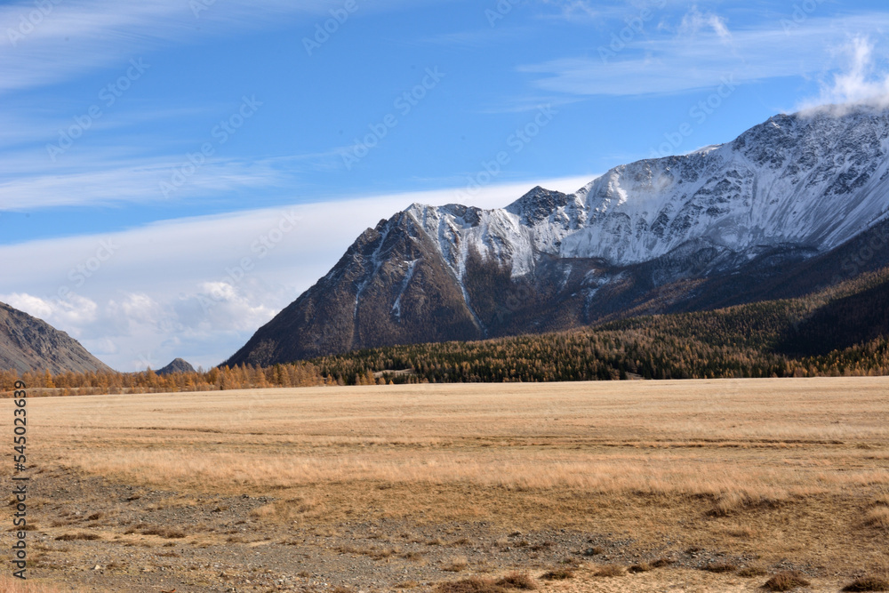 Snow-capped peaks of a large mountain range along the edge of the autumn steppe.