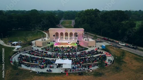 People attend entertainment event in Taggart amphitheater of riverside park, Indianapolis in Indiana. Aerial tilt down rising photo