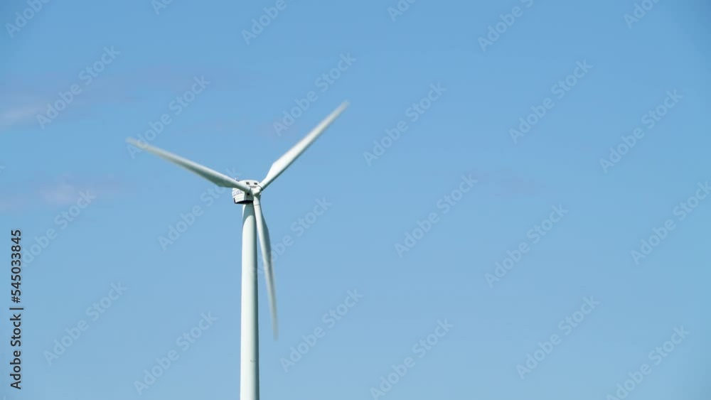 Fast spinning wind power turbine in agriculture fields, tilt up view Fast spinning wind power turbine in agriculture fields, tilt up view
