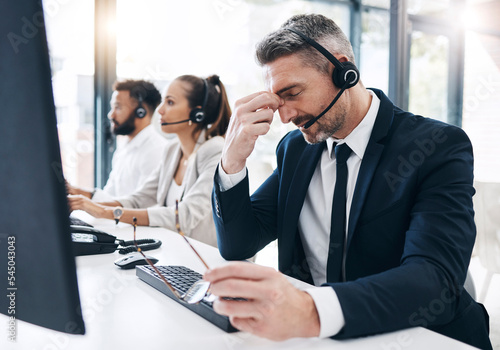 Call center, customer service and man with headache, stress and tired of working in office. Burnout, crm and frustrated male telemarketing consultant in customer support on call with difficult client