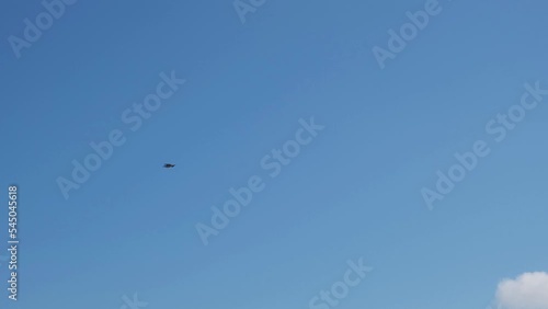 A man in a wetsuit on a parachute rides a board on the waves of the sea. A young man performs a trick in the air against the sky. Water sports, kitesurfing, paragliding, hydrofoil, surfing photo