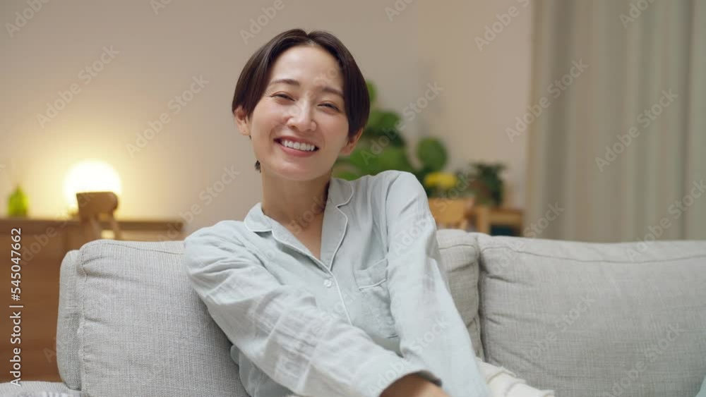 夜リビングで寛ぐ笑顔のミドル女性 夜リビングで寛ぐ笑顔のミドル女性