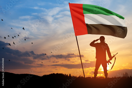 Silhouette of soldier saluting with the flag of UAE against sunset or sunrise. Concept of national holidays. Commemoration Day.