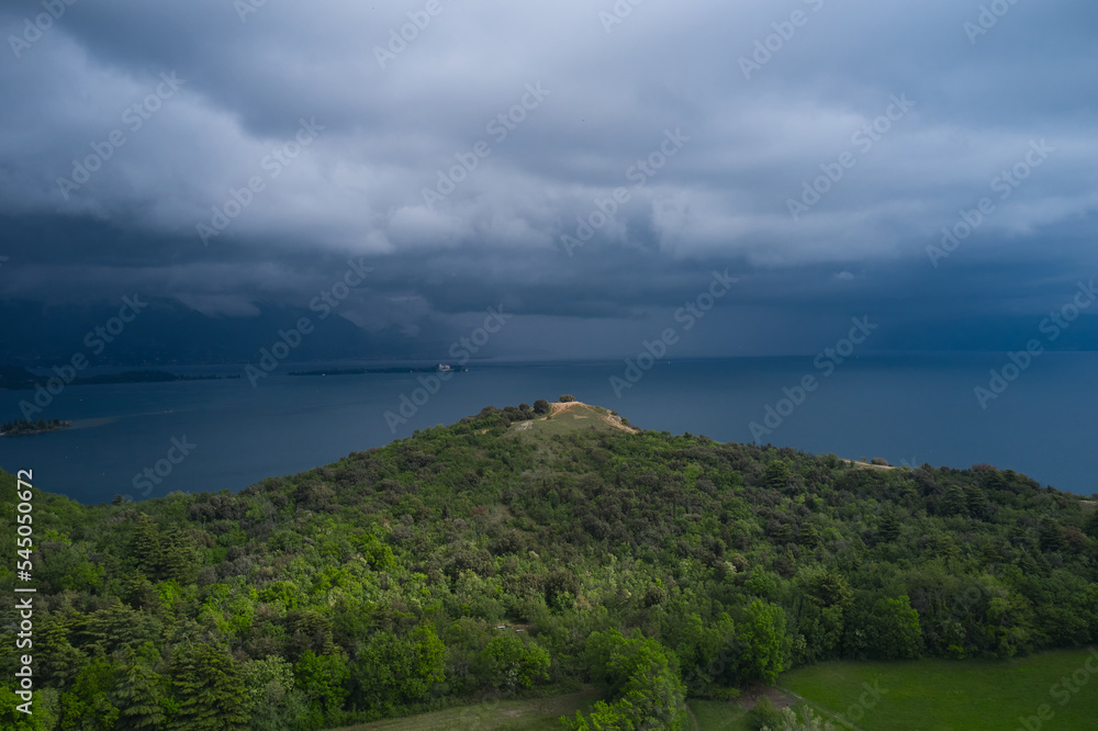 Aerial view of Punta Sasso at Lake Garda, Italy. Gray clouds, coastline of a large lake in the Alps. Rain clouds over the Alps Lake Garda.