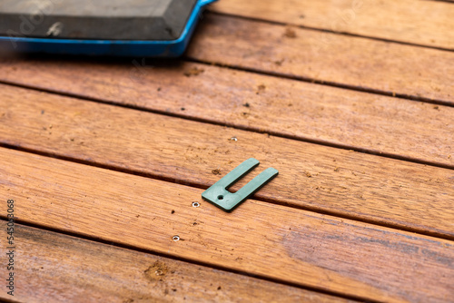 A horseshoe tool laying on the wooden planks of a backyard construction
