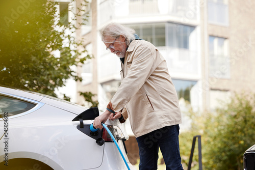 Senior man charging electric car photo