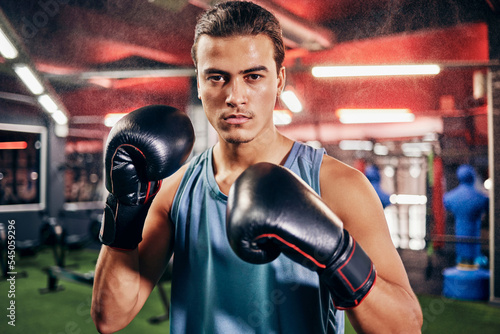 Fitness, sports or motivation man boxer in gym studio with gloves for training, cardio workout or exercise. Focus, mma portrait or male athlete in boxing ring with goal vision, health or fight energy © Beaunitta V W/peopleimages.com